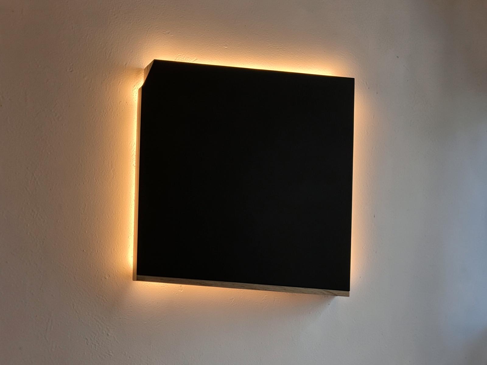 Matt svart panel på en vägg med varm LED-ljusram bakom